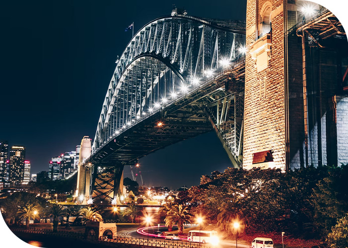 A low angle of the Sydney Harbour Bridge being lit up by lights at night
